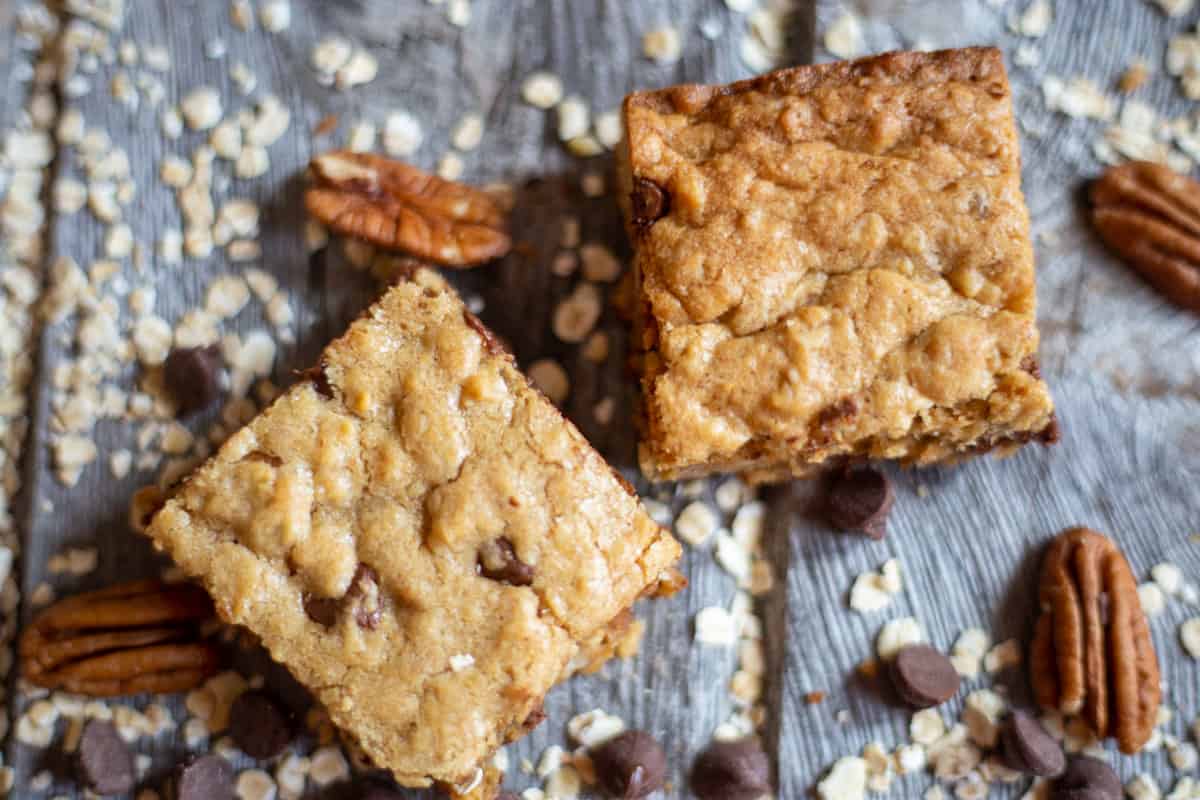 Oatmeal Chocolate chip and peanut butter square on board with loose pecans, oatmeal and chocolate chips