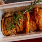 roasted sweet potatoes in casserole dish with sprig of rosemary