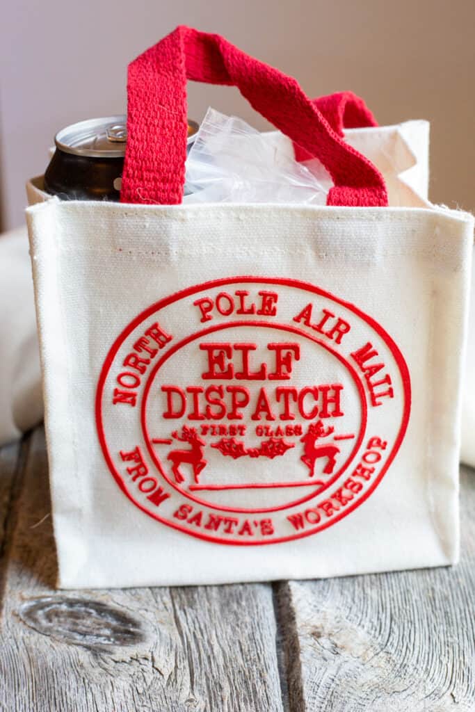 A Christmas gift bag containing a can of beer and Herbed Beer Bread Mix. The bag is red and white.