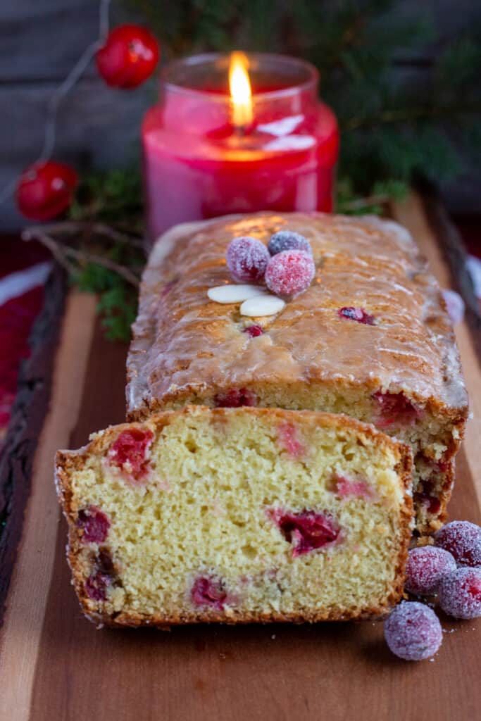Cranberry orange bread sliced and served on wooden board.