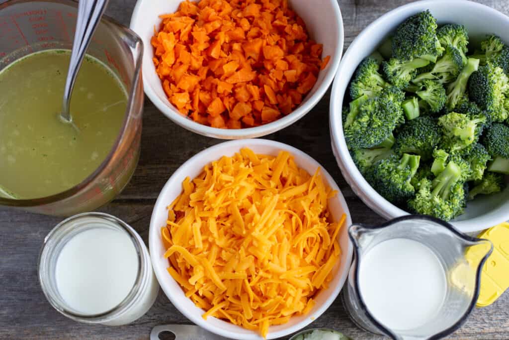 Broccoli Cheddar Soup in a white bowl with a spoon to the left of the bowl. The bowl is surrounded by teal coloured napkin.