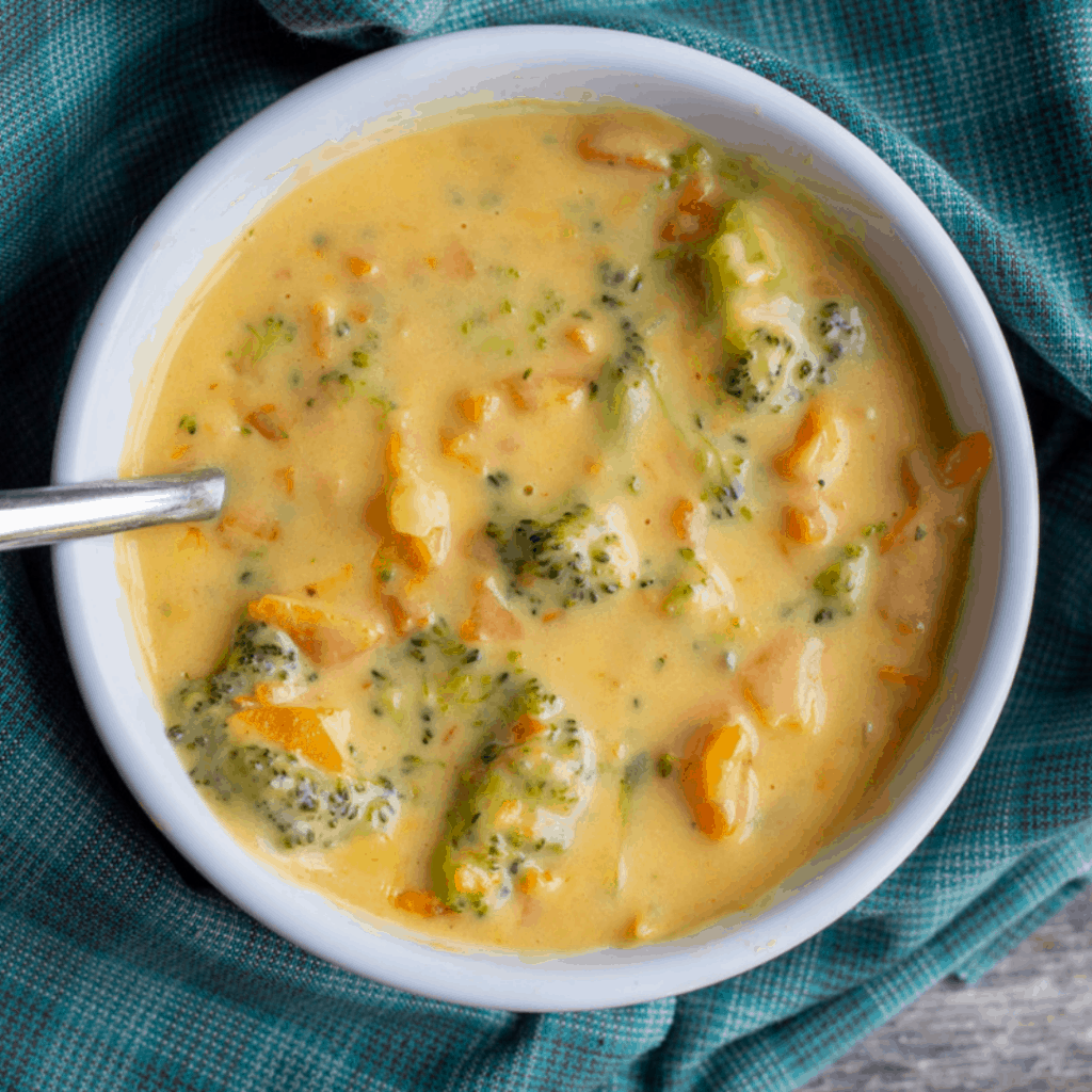 Broccoli Cheddar Soup in white bowl with spoon.