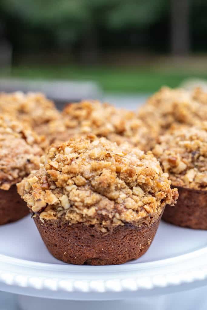 Bakery style banana nut muffins on white plate.