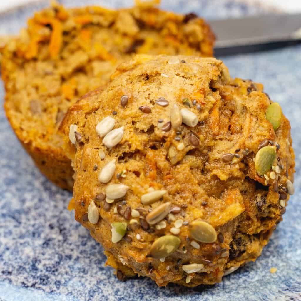 Close up image of Morning Glory Muffins on a blue plate sliced in half.