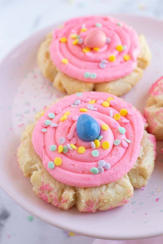 Frosted sugar cookies on pink plate.
