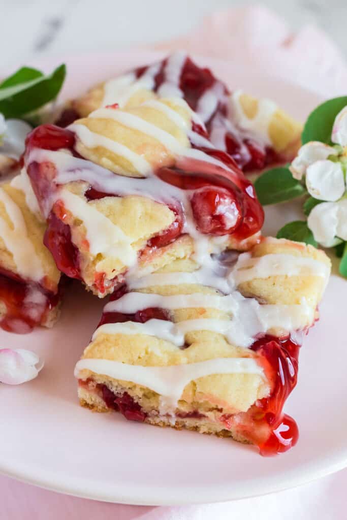 Cherry pie bars served on a pink plate.
