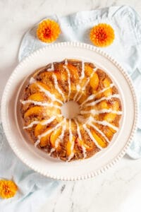 Peach cobbler pound cake with glaze on white plate.