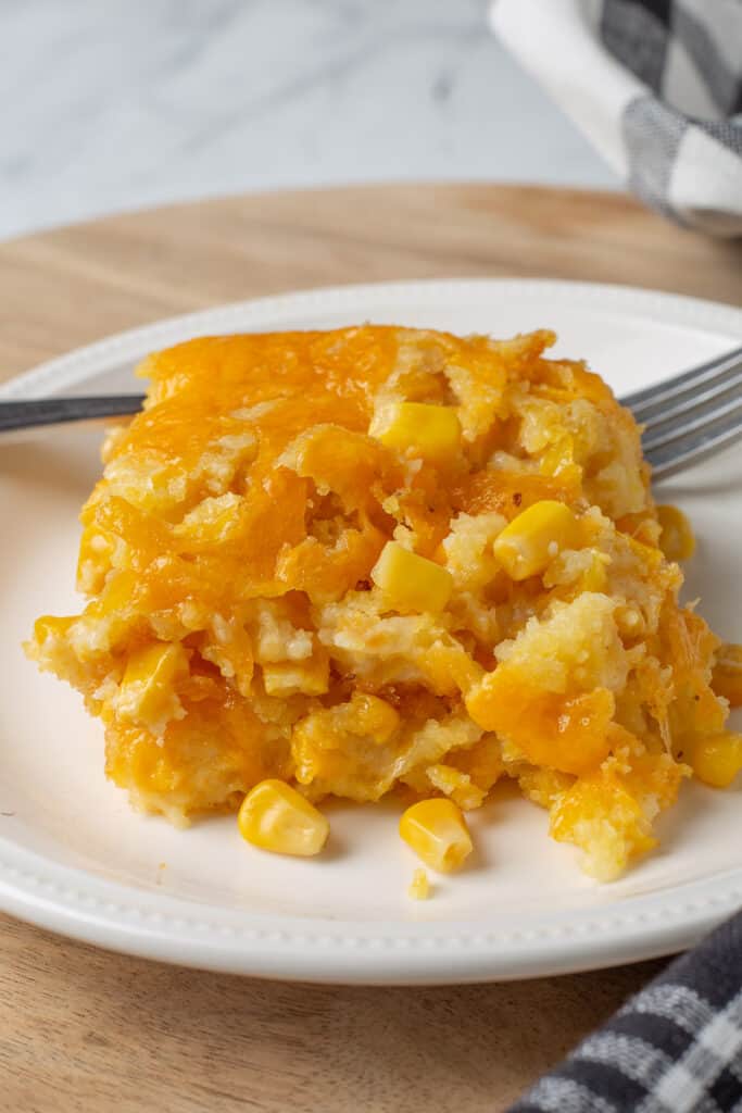 Corn casserole on white plate with fork.