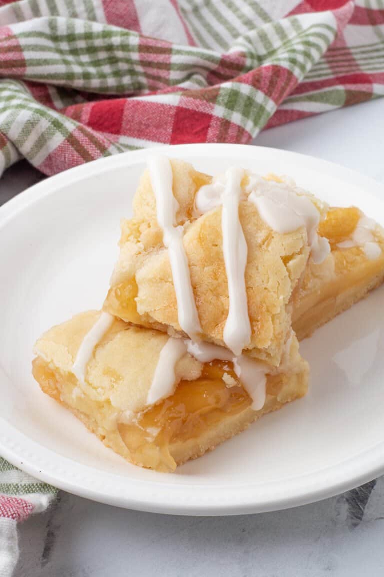 Glazed apple pie bars on white plate.
