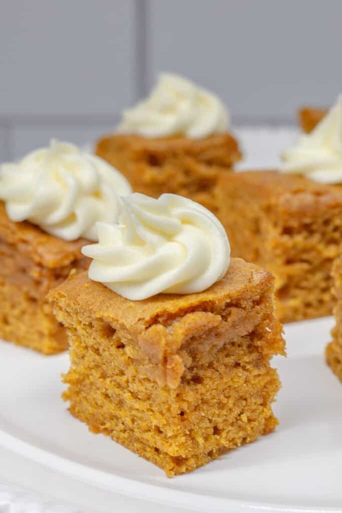 Four pieces of pumpkin bars on white plate.