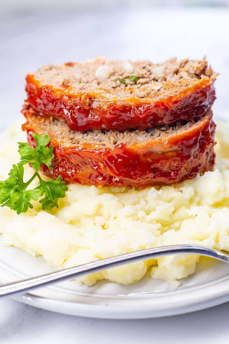 Two slices of meatloaf on a bed of mashed potatoes.