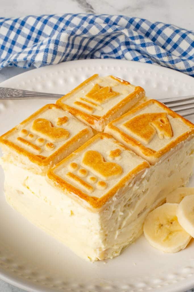 Not yo mama's banana pudding helping on a white plate with sliced bananas and a fork.