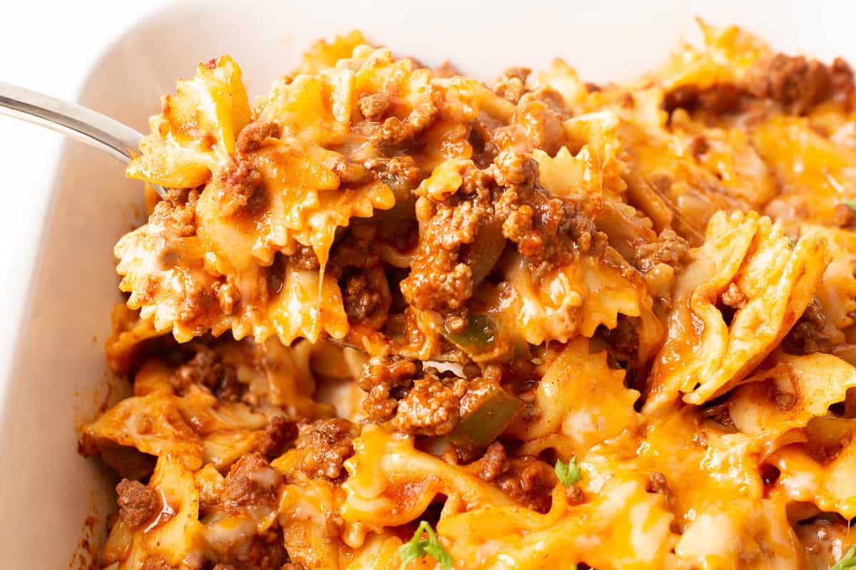 Scoop of sloppy joe casserole on spoon held over casserole dish.
