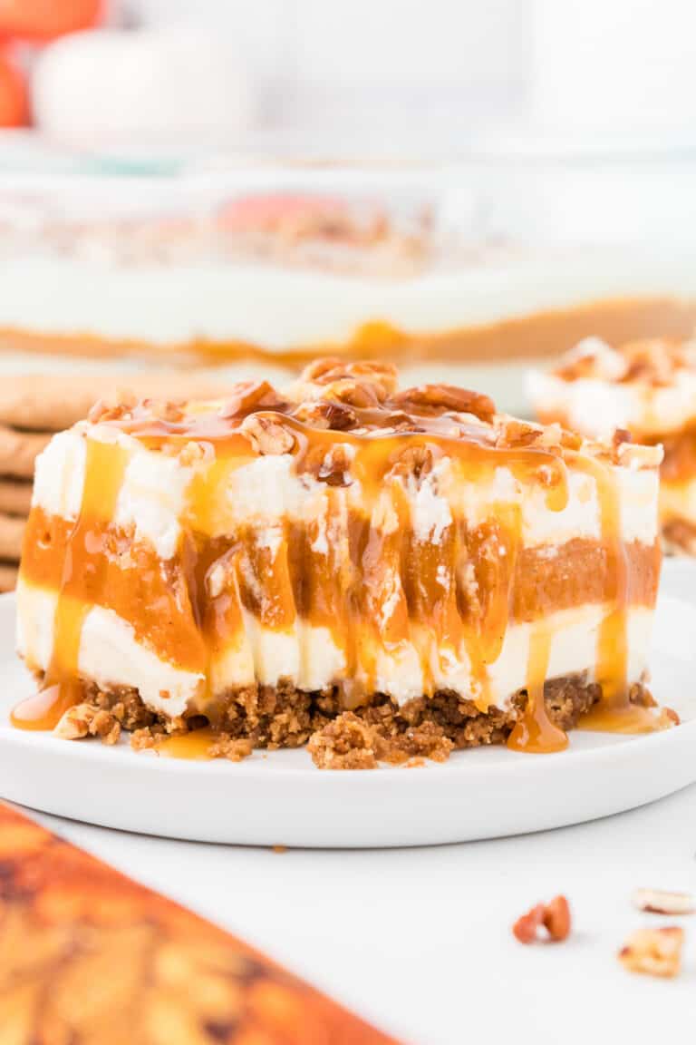 No bake pumpkin delight on a white plate, drizzled with. caramel topping and crumbled pecans.