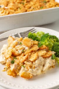 Poppy seed chicken casserole on a white plate with steamed broccoli.