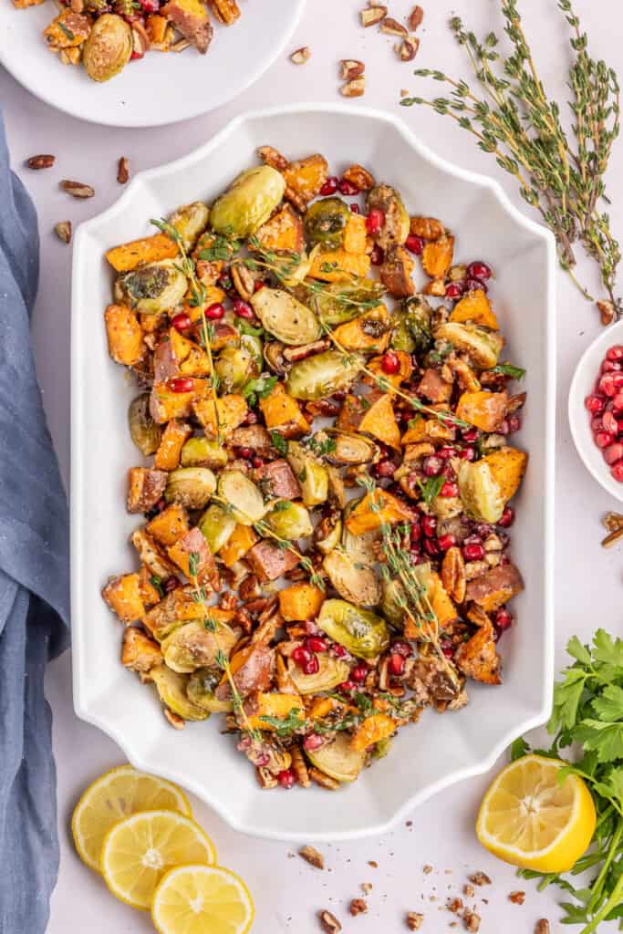 Roasted brussels sprouts with sweet potatoes in white casserole dish.