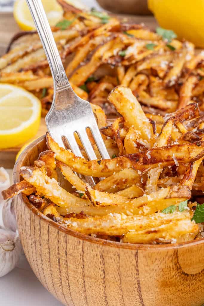 Air fryer french fries with garlic and parmesan in brown bowl with fork.