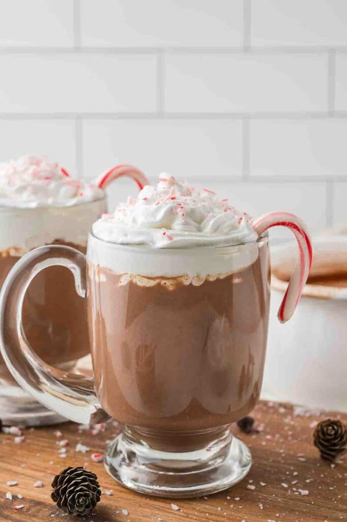 Peppermint hot chocolate in a glass mug with a candy cane.