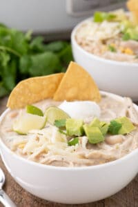 Slow cooker white chicken chili in a bowl with tortillas.
