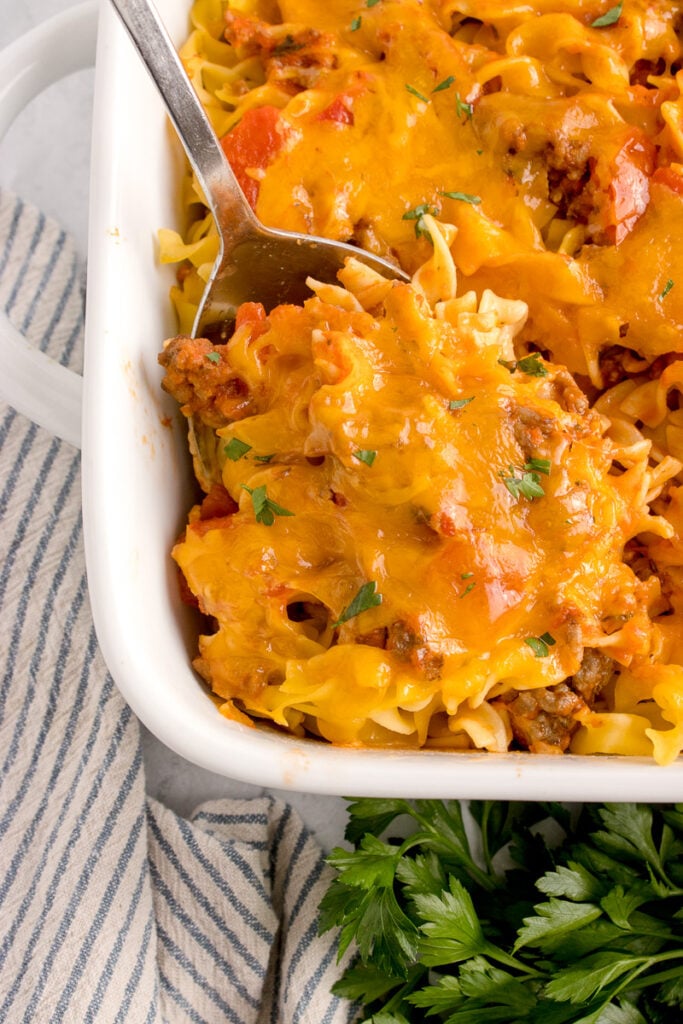 Ground beef and egg noodle caserole scooped up on serving spoon.