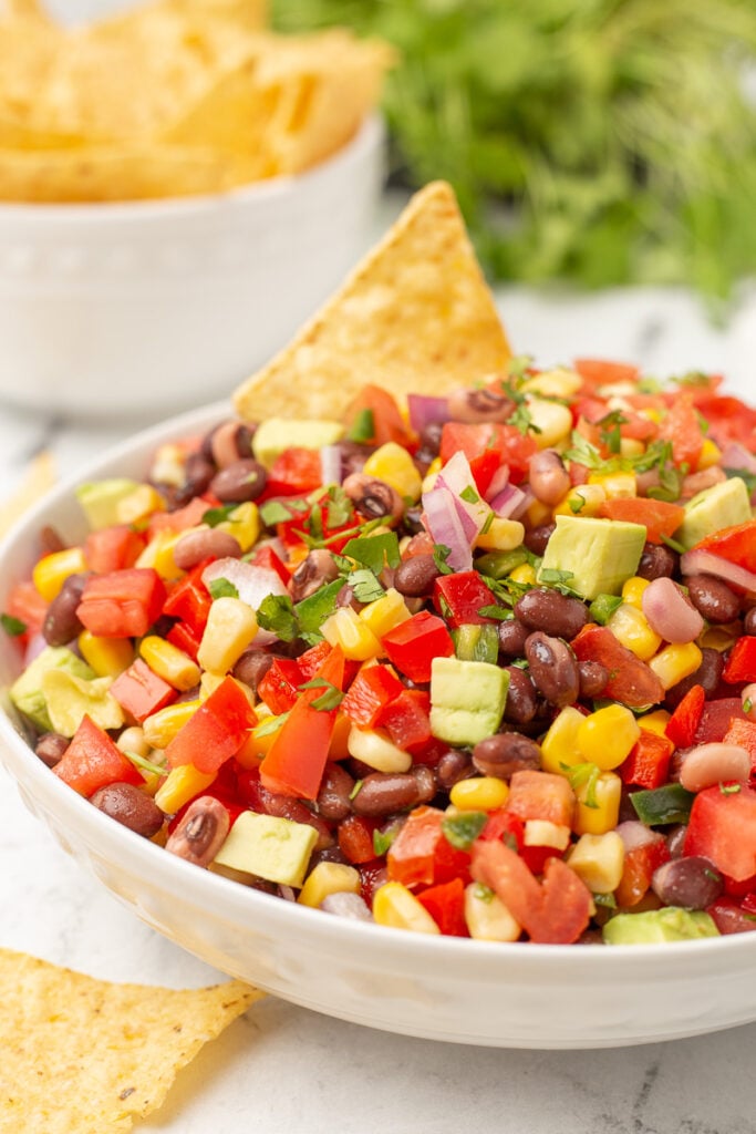 Cowboy caviar in a white bowl with nachos on the side.