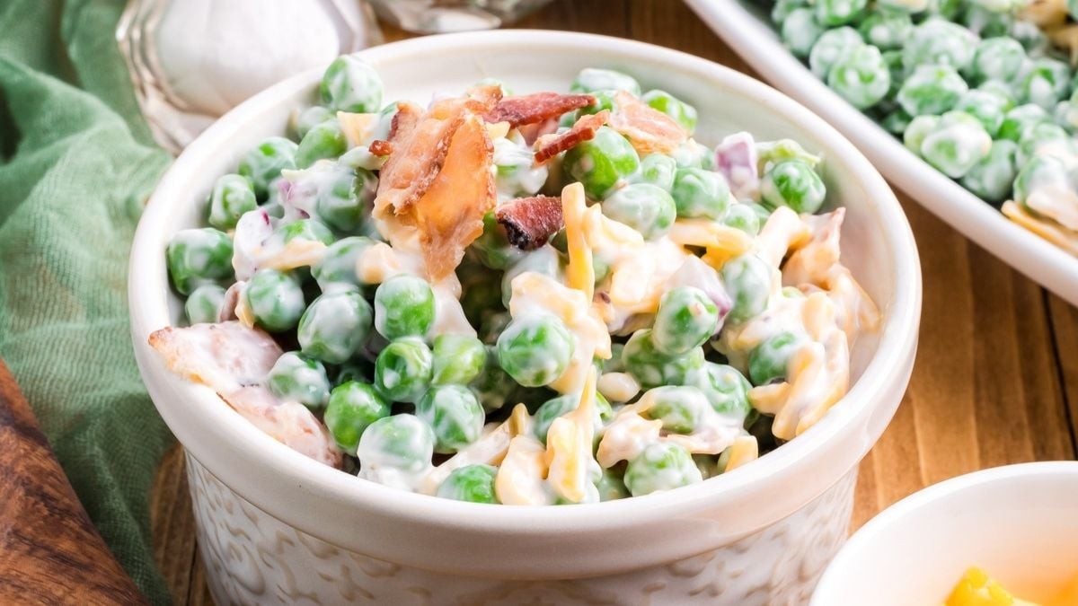 Creamy pea salad served in a white bowl.