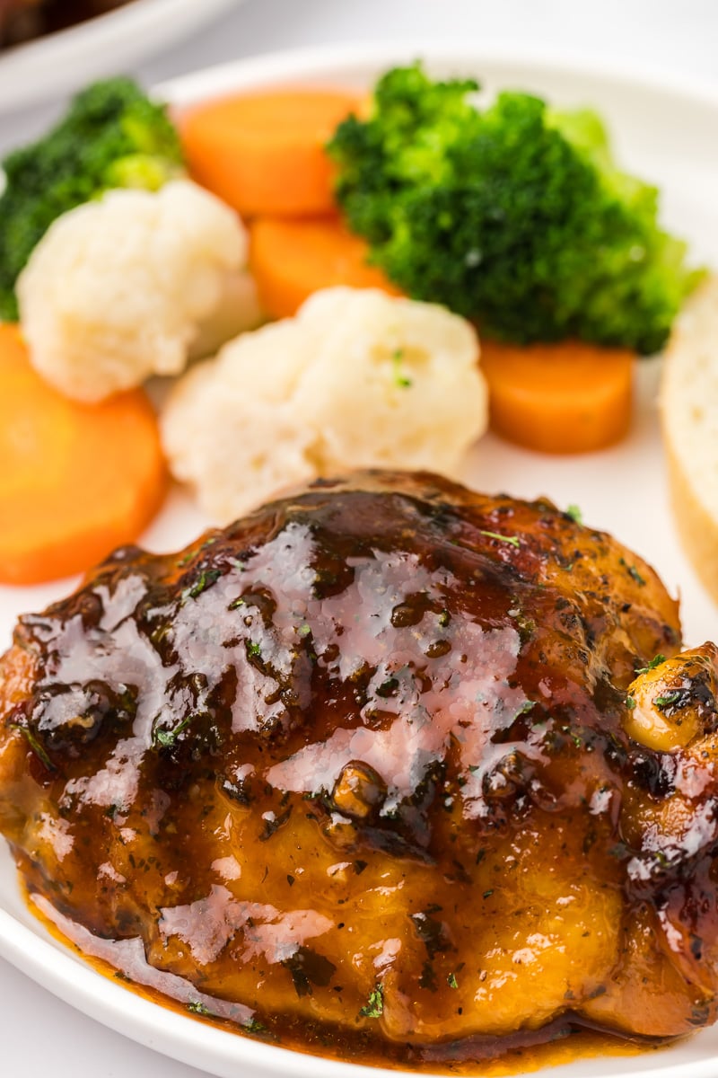 Crockpot chicken thighs on a white plate.