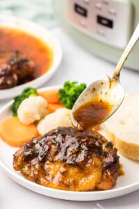 Slow cooker bbq chicken thigh on a plate with fresh vegetables.