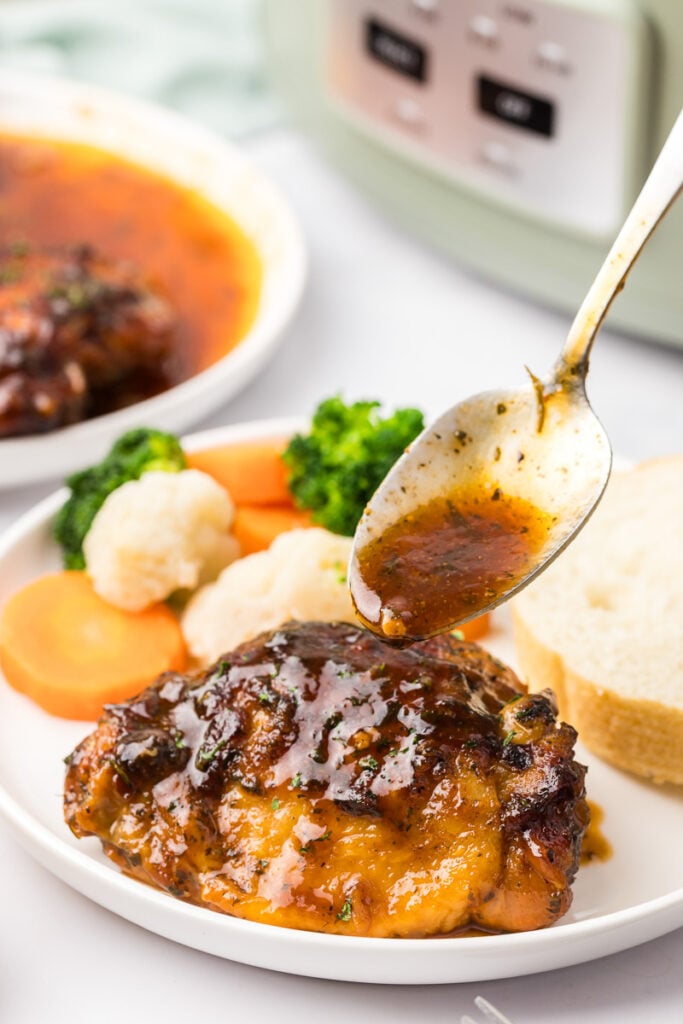 Slow cooker bbq chicken thigh on a plate with fresh vegetables.