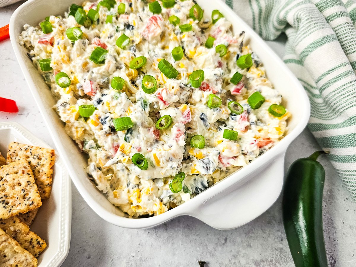 Creamy ranch dip in white serving container with crackers on the side.