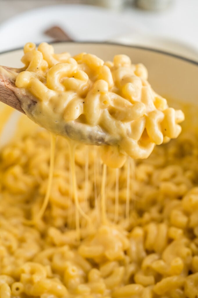 Scoop of mac and cheese held over dish of remaining mac and cheese.