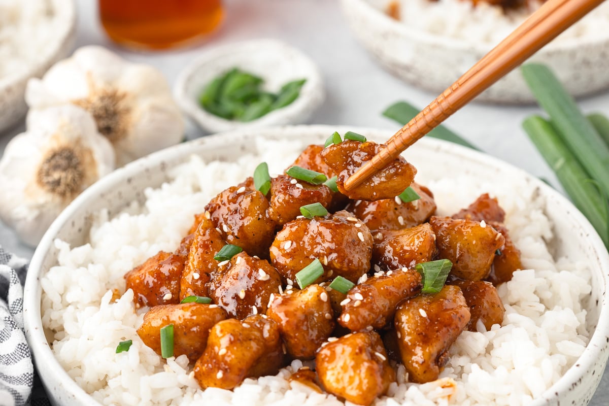 Honey garlic chicken bites on a plate of rice.