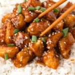 Honey garlic chicken bites on a white plate with rice.