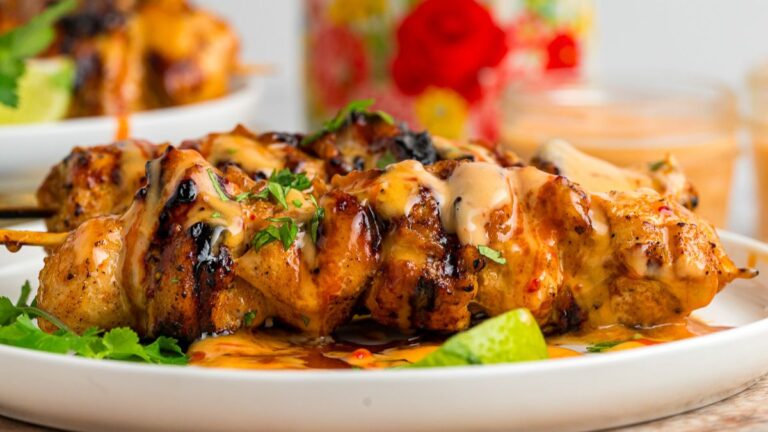 Bang bang chicken skewers on a white plate.