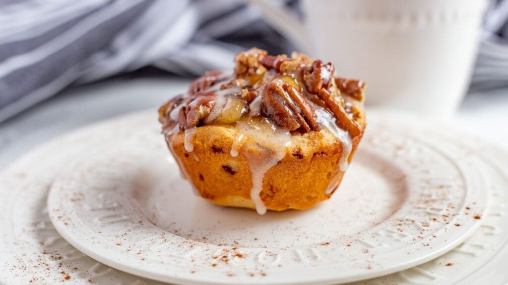 Cinnamon roll apple pie cup on a plate.