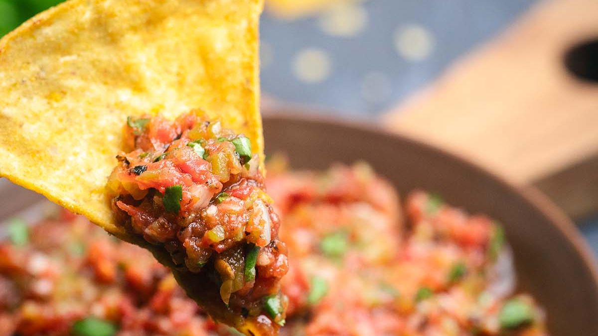 Close up image of a salsa chip with fire roasted salsa.