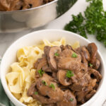 Beef stroganoff in a small white bowl with noodles.
