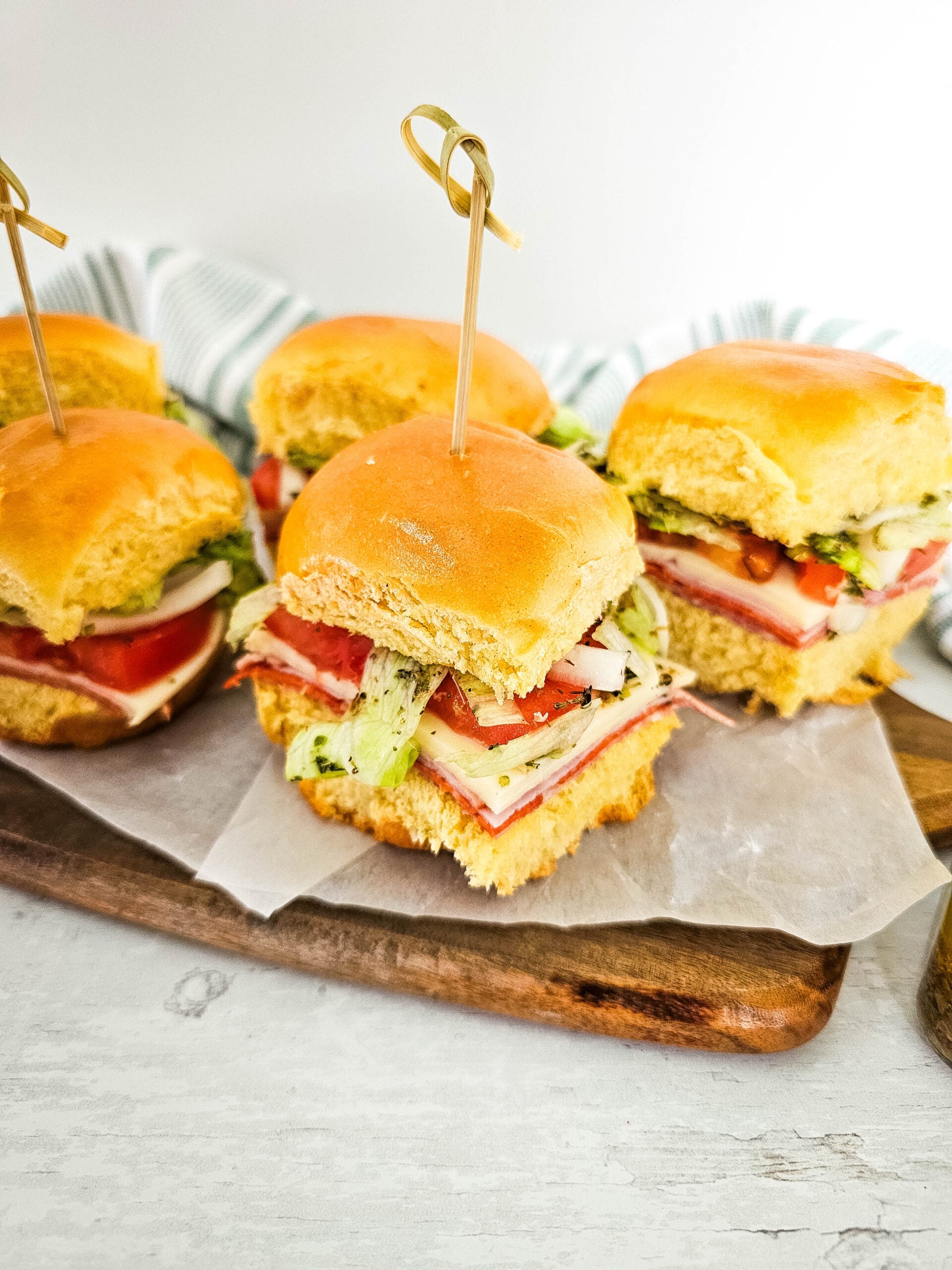 Cold Italian sliders served on a wooden board.
