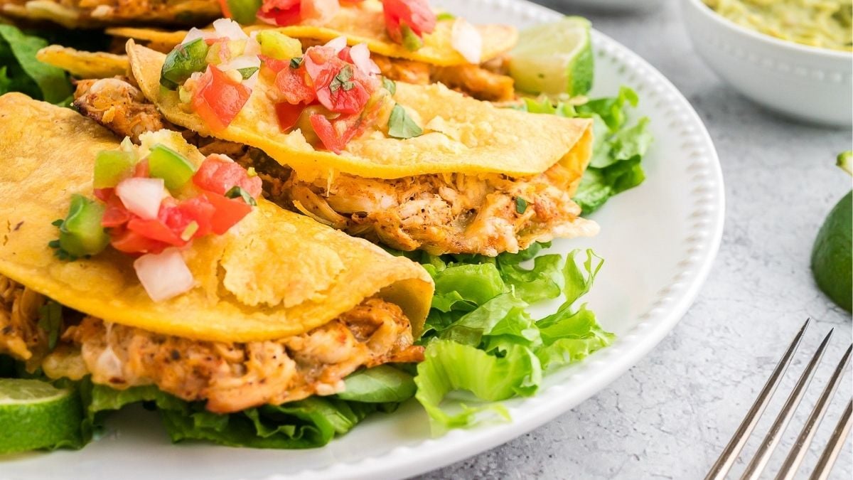 Baked chicken tacos served on a white plate.