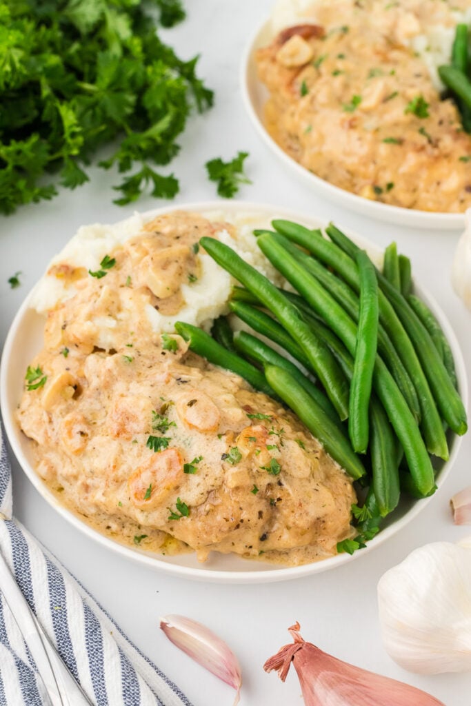 Creamy garlic chicken on a plate with green beans.