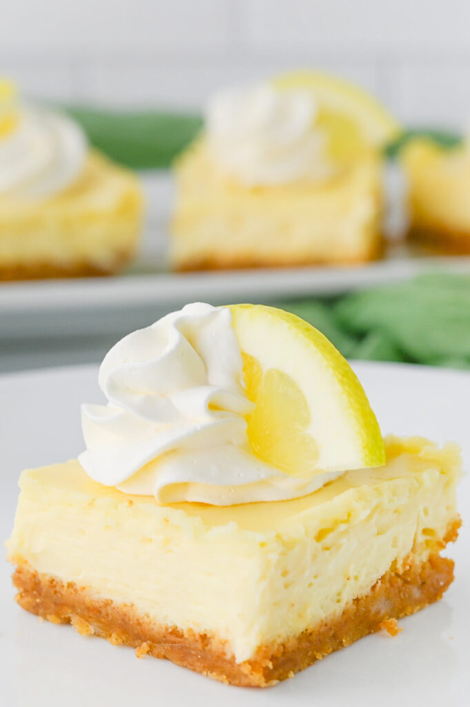 Lemon cheesecake bars on a white plate.