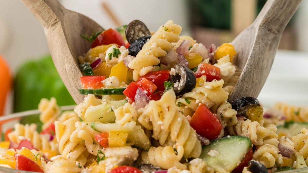 Greek pasta salad scooped up with salad tongs.