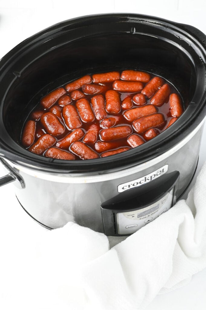Crockpot little smokies in slow cooker ready to be served for a tailgating party.