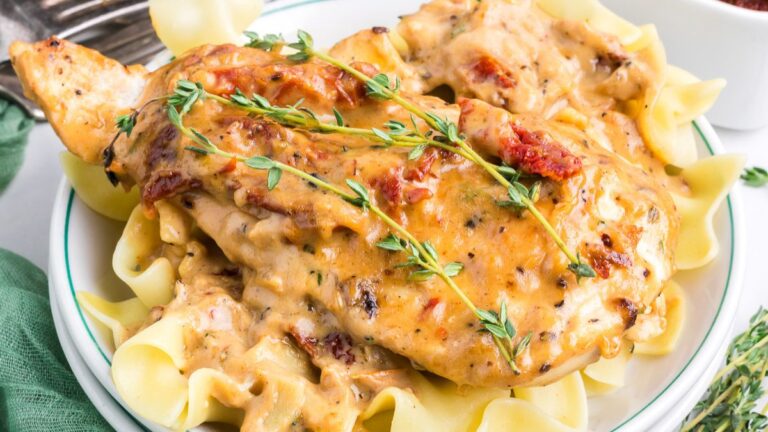 Marry me chicken served on a bed of noodles on a plate.