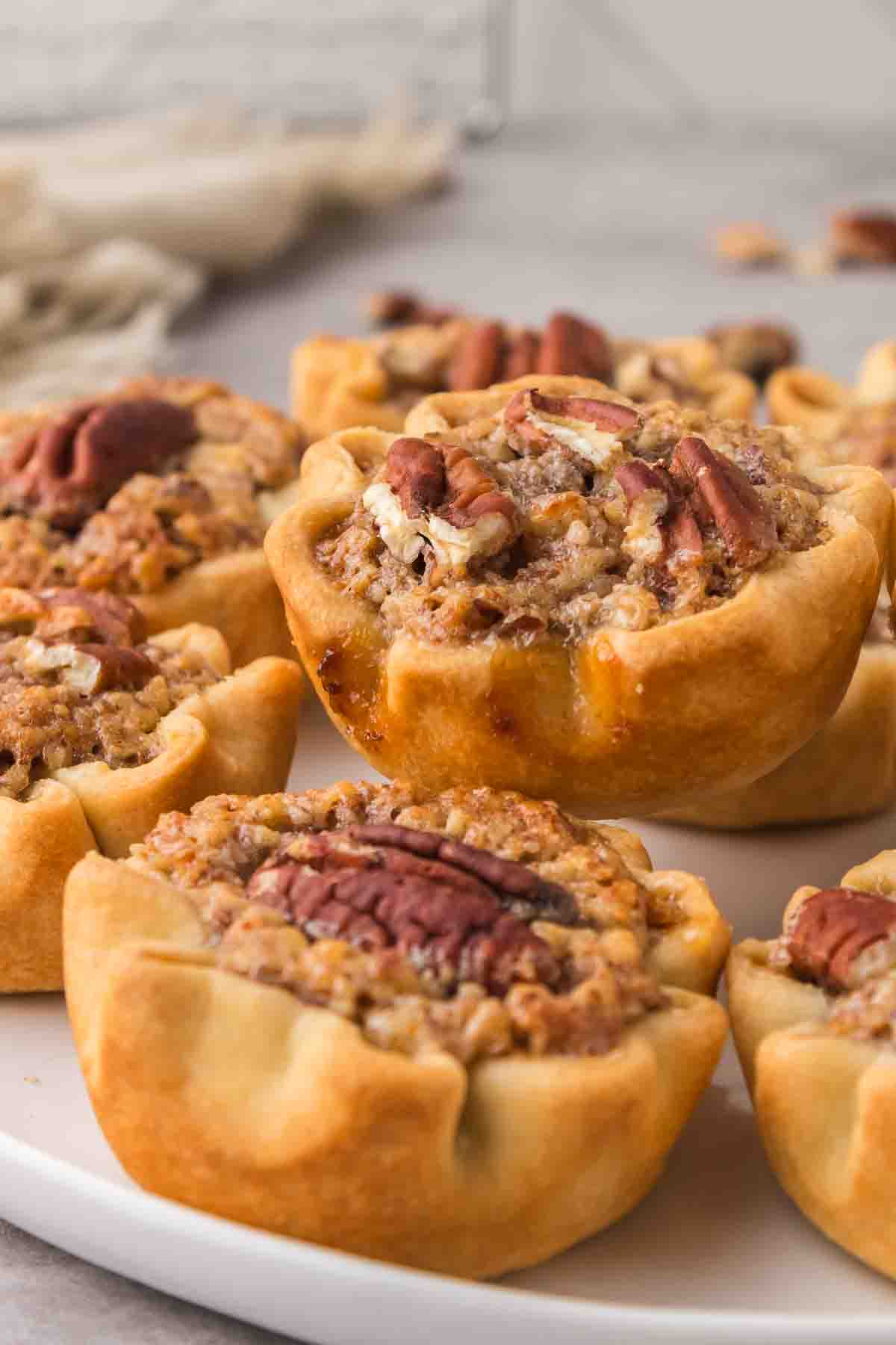 Mini pecan pies stacked on a white plate.