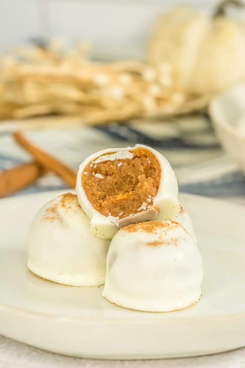 Mini pumpkin cake balls stacked on a white plate.