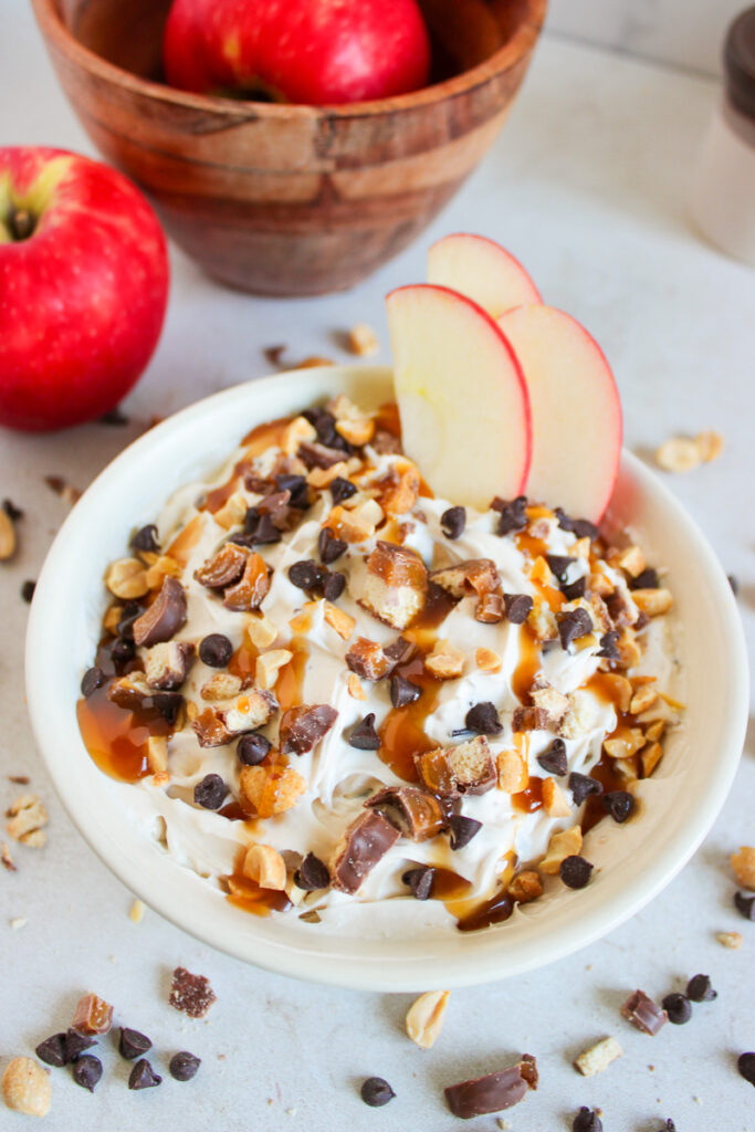 Caramel apple dip with Twix bars in a white bowl.