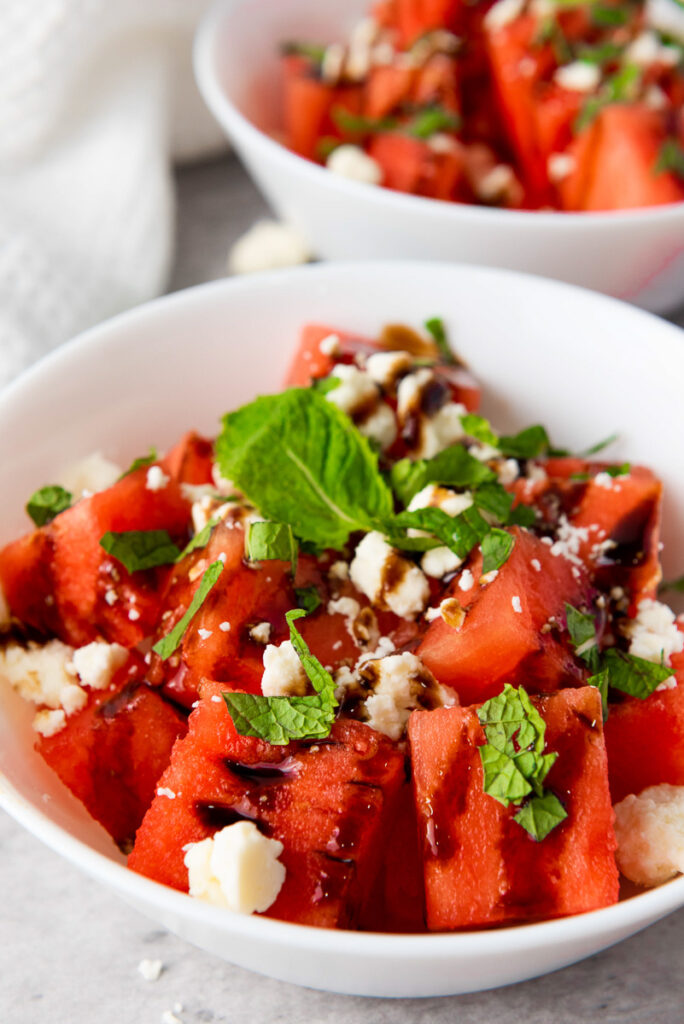 Watermelon salad with feta and balsamic vinegar in a white bowl.