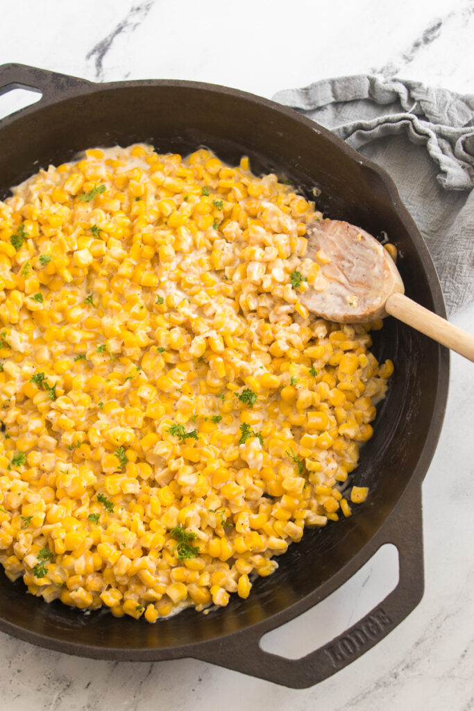 Honey butter skillet corn in skillet with a wooden spoon.