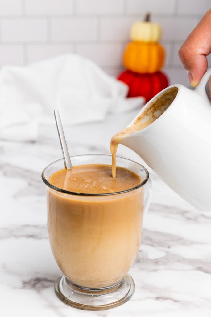 Pumpkin spice coffee cream is poured into cup of coffee.